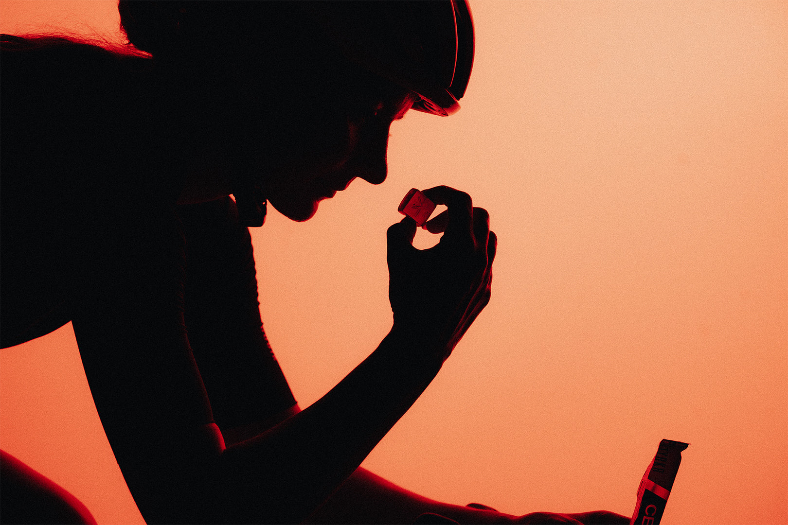 Silhouette of a person holding a small object against an orange background